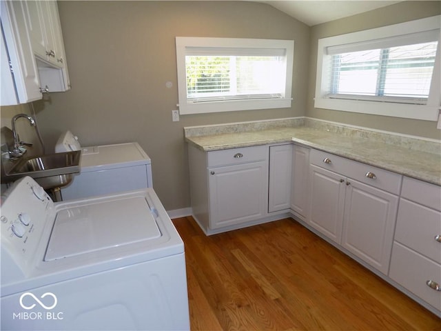 laundry area with sink, cabinets, separate washer and dryer, and wood-type flooring