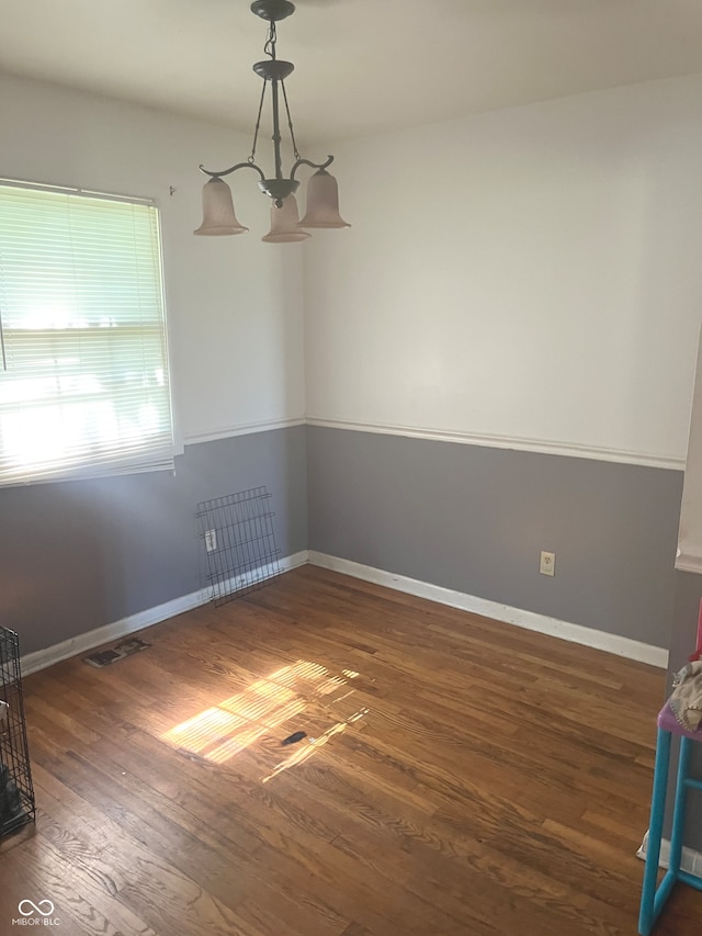 unfurnished room with an inviting chandelier and dark wood-type flooring