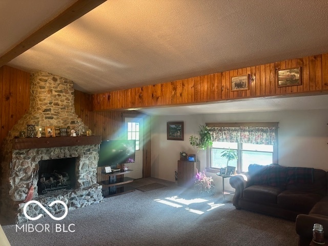 living room with lofted ceiling with beams, a textured ceiling, wood walls, and a stone fireplace