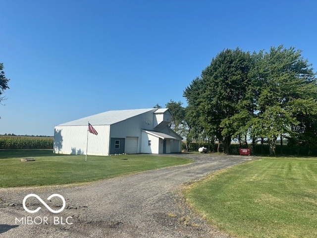 view of side of property featuring an outdoor structure, a garage, and a yard