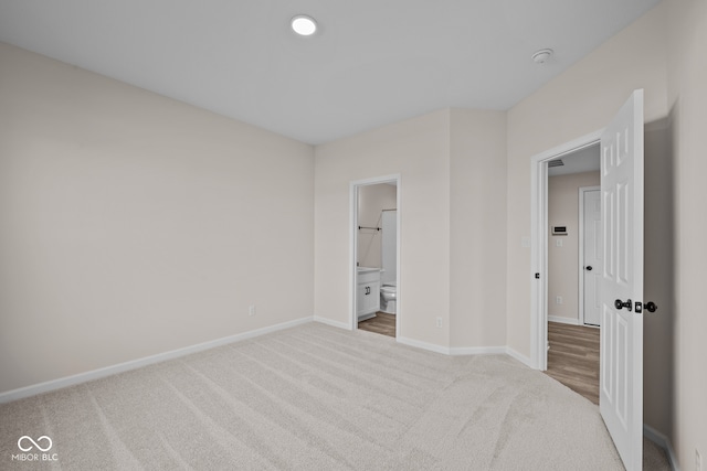 unfurnished bedroom with ensuite bath and light colored carpet