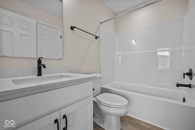 full bathroom with toilet, hardwood / wood-style floors, vanity, and washtub / shower combination