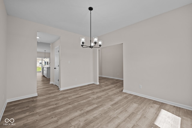 unfurnished dining area with a notable chandelier and light wood-type flooring