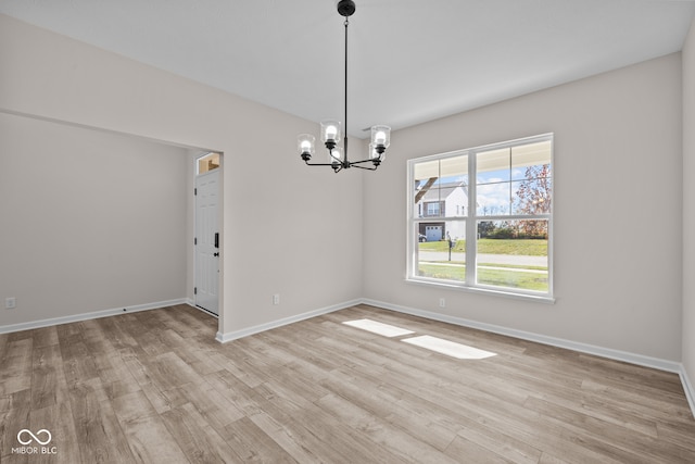 unfurnished room with an inviting chandelier and light hardwood / wood-style floors