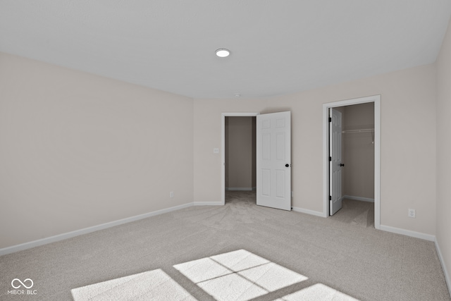 unfurnished bedroom featuring a spacious closet, light carpet, and a closet