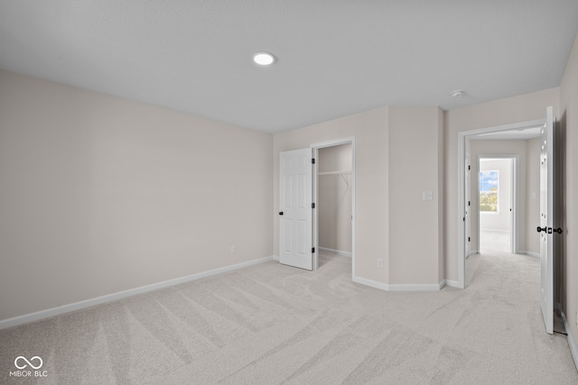 unfurnished bedroom with a closet, light carpet, and a walk in closet