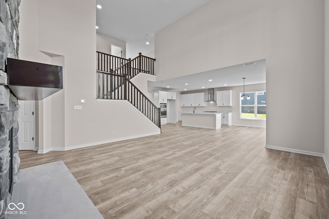 living room featuring a towering ceiling, light hardwood / wood-style flooring, and a fireplace