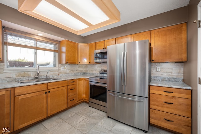 kitchen with appliances with stainless steel finishes, tasteful backsplash, light stone counters, and sink