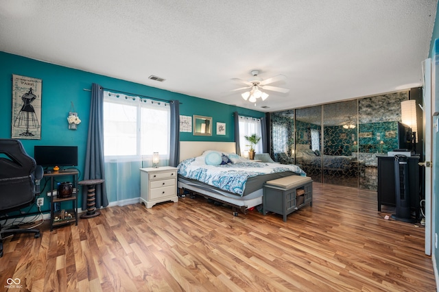 bedroom with a textured ceiling, light hardwood / wood-style floors, and ceiling fan