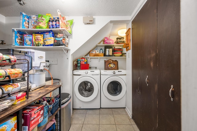 laundry area featuring washer and dryer, light tile patterned flooring, and a textured ceiling