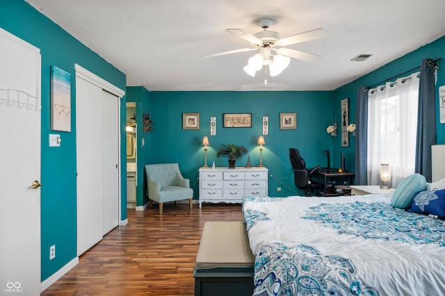 bedroom with a textured ceiling, ceiling fan, a closet, and dark hardwood / wood-style floors