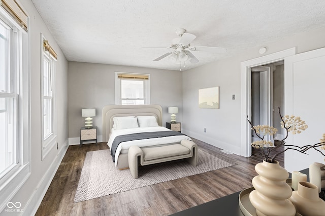 bedroom featuring dark wood-type flooring, multiple windows, ceiling fan, and a textured ceiling