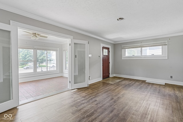 foyer entrance featuring hardwood / wood-style flooring, ornamental molding, a textured ceiling, and a healthy amount of sunlight