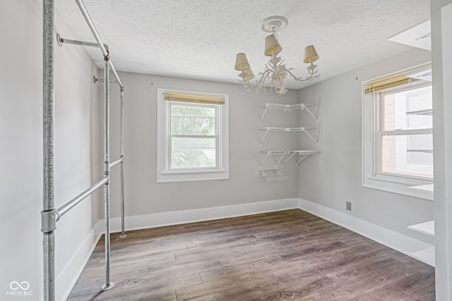 spare room with a textured ceiling, an inviting chandelier, and hardwood / wood-style floors