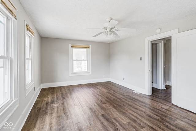 unfurnished room with a healthy amount of sunlight, ceiling fan, and dark hardwood / wood-style flooring