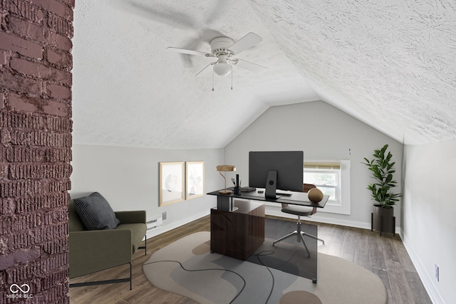 home office with lofted ceiling, hardwood / wood-style floors, and a textured ceiling