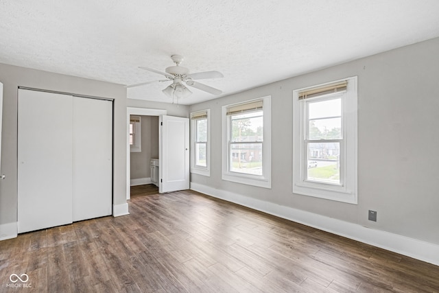 unfurnished bedroom with a textured ceiling, a closet, connected bathroom, hardwood / wood-style flooring, and ceiling fan