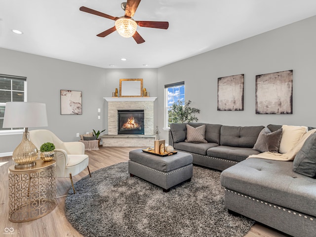 living room with wood-type flooring, a fireplace, and ceiling fan