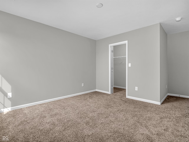 unfurnished bedroom with a closet, carpet flooring, and a spacious closet