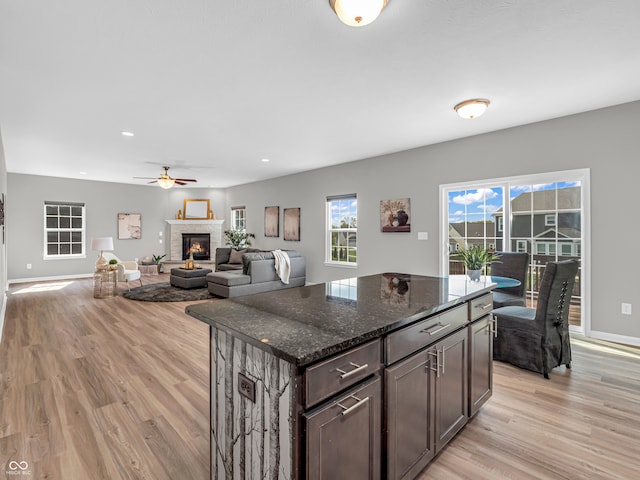 kitchen with dark stone counters, dark brown cabinetry, light hardwood / wood-style floors, and a fireplace