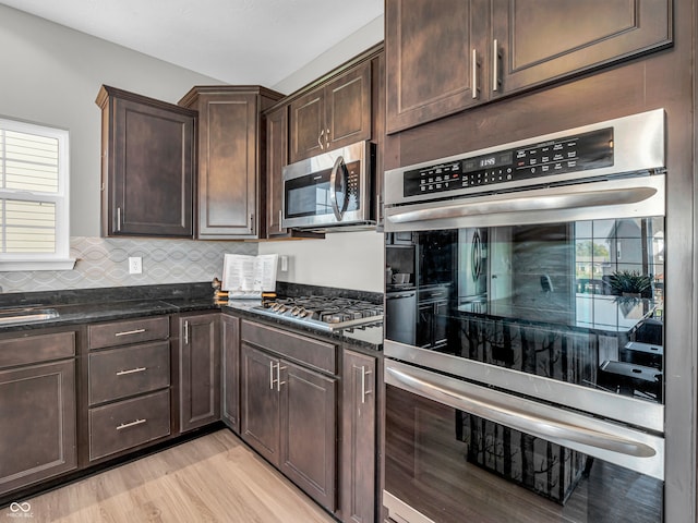 kitchen featuring light wood-type flooring, backsplash, dark brown cabinets, and stainless steel appliances