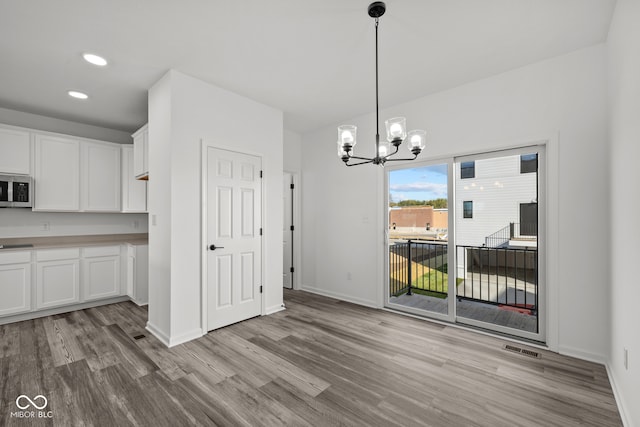 unfurnished dining area featuring light hardwood / wood-style flooring and an inviting chandelier