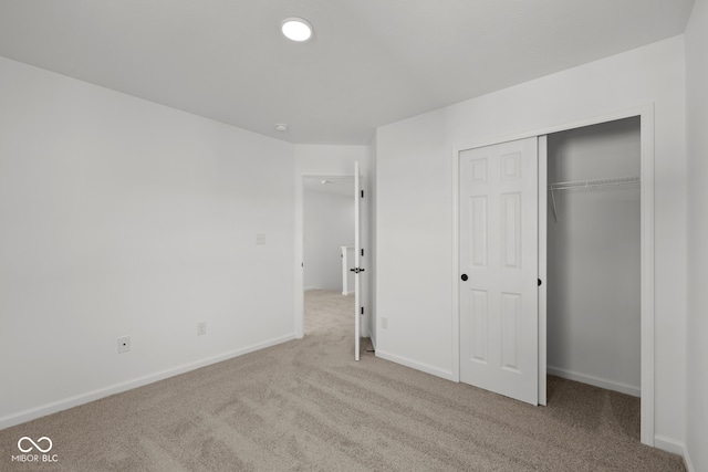 unfurnished bedroom with light carpet and a closet