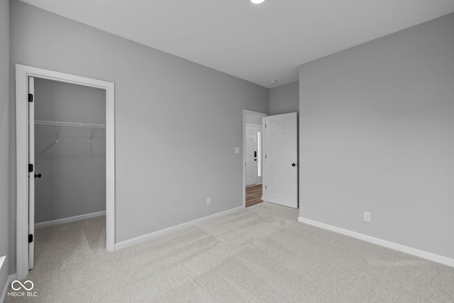 unfurnished bedroom featuring light carpet, a closet, and a spacious closet