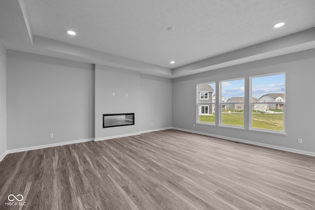 unfurnished living room with a textured ceiling and light hardwood / wood-style flooring