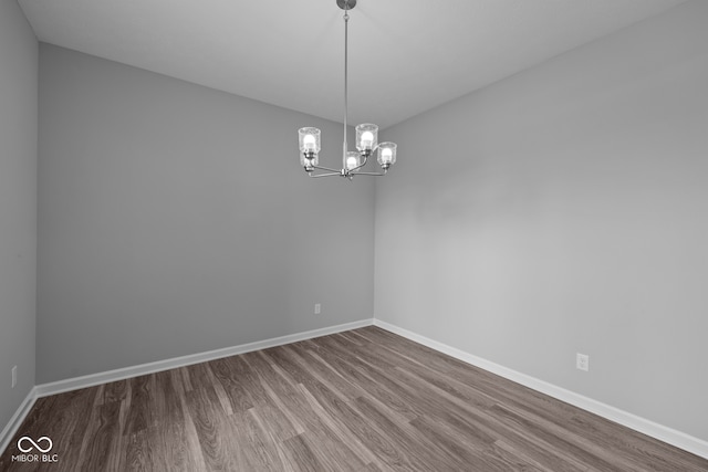 unfurnished room featuring wood-type flooring and a chandelier