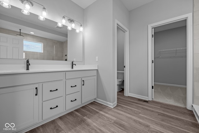 bathroom with toilet, vanity, hardwood / wood-style floors, and tiled shower