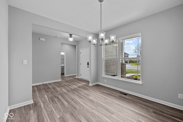 unfurnished dining area featuring a notable chandelier and hardwood / wood-style flooring