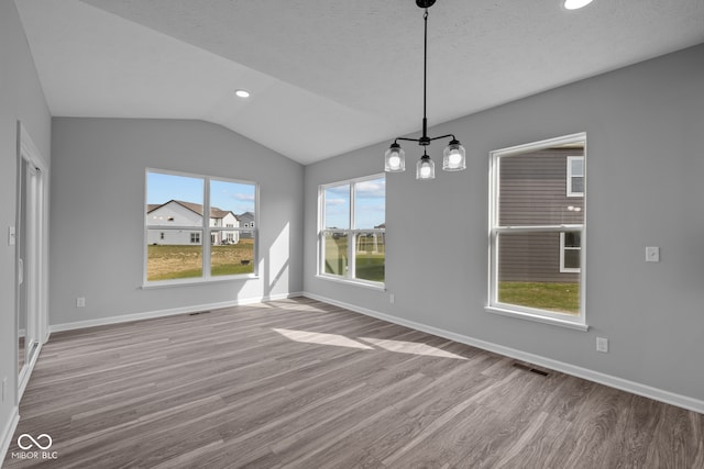 unfurnished dining area featuring vaulted ceiling, light hardwood / wood-style floors, and a textured ceiling