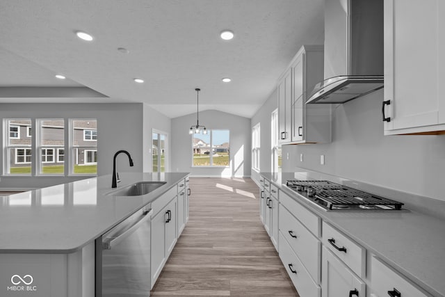 kitchen featuring white cabinetry, sink, appliances with stainless steel finishes, an island with sink, and wall chimney range hood