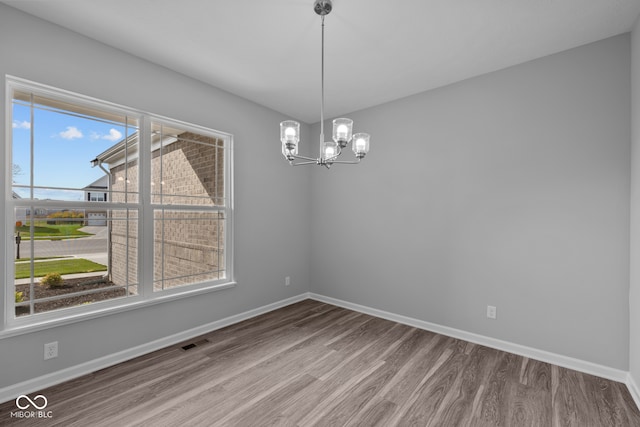 unfurnished dining area featuring plenty of natural light, wood-type flooring, and a chandelier