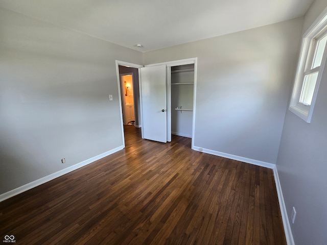 unfurnished bedroom featuring a closet and dark hardwood / wood-style flooring