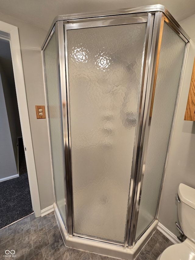 bathroom featuring tile patterned flooring, toilet, and a shower with door