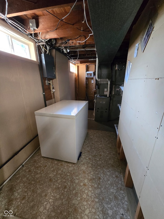 basement with tile patterned floors, heating unit, and fridge