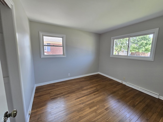 unfurnished room featuring dark wood-type flooring, baseboard heating, and baseboards