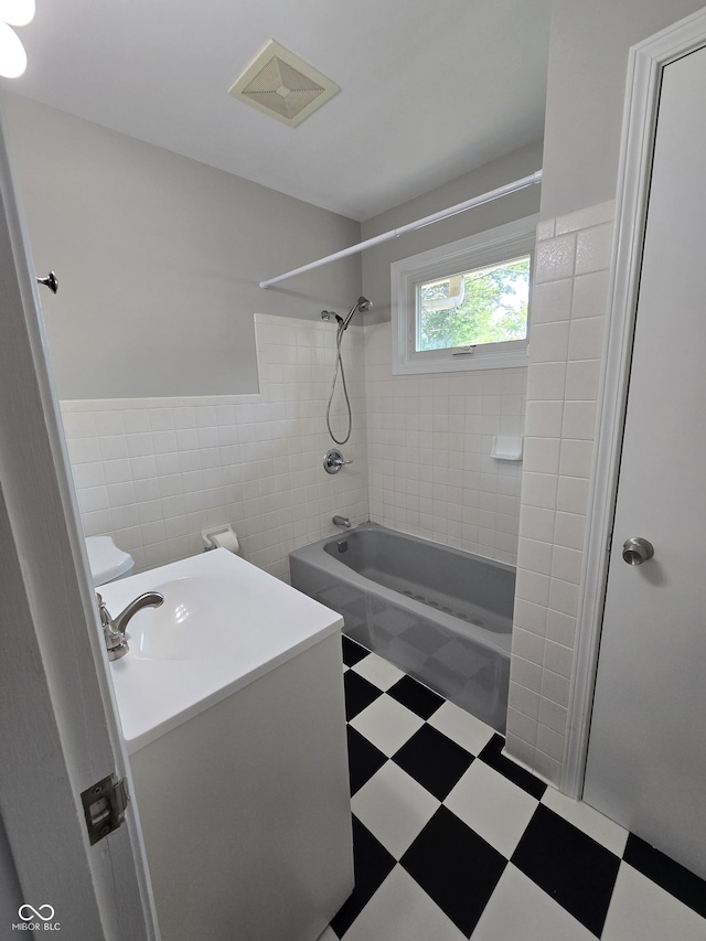 bathroom featuring tile walls, visible vents, vanity,  shower combination, and tile patterned floors