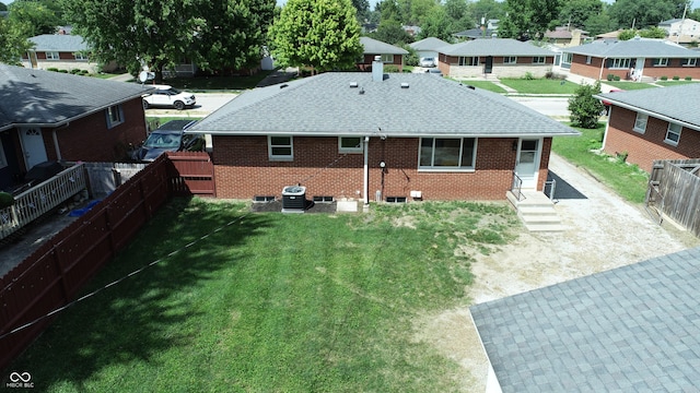 rear view of property with a shingled roof, a residential view, brick siding, and fence