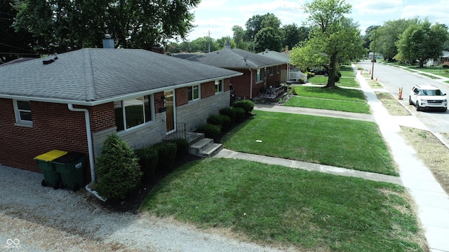 view of property exterior with roof with shingles, a lawn, and brick siding