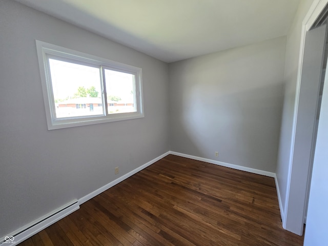 unfurnished room with dark hardwood / wood-style floors and baseboard heating