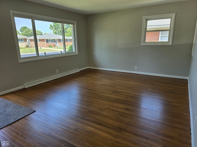 empty room featuring a baseboard heating unit and dark hardwood / wood-style floors