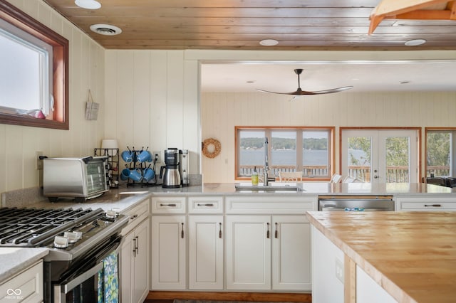 kitchen featuring white cabinets, appliances with stainless steel finishes, french doors, and wooden walls