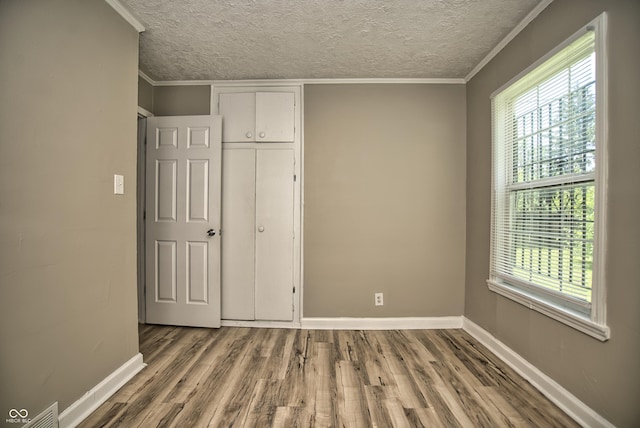 unfurnished bedroom with crown molding, wood finished floors, visible vents, and a textured ceiling