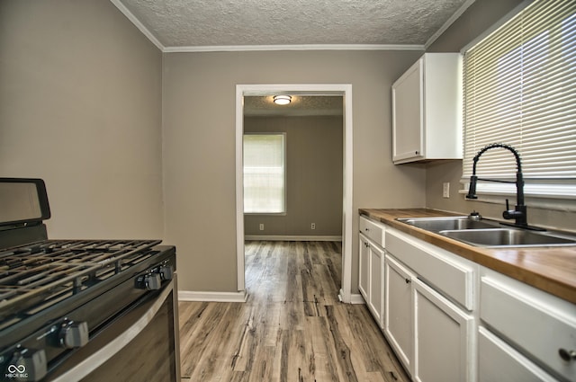 kitchen with gas stove, a sink, a textured ceiling, white cabinetry, and light wood-type flooring