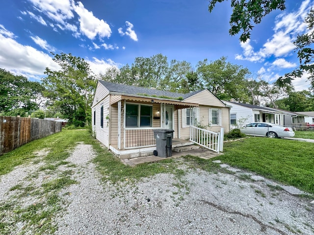 view of front of house with driveway, a porch, a front lawn, and fence