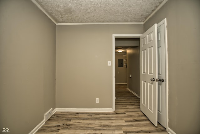 spare room with wood finished floors, baseboards, electric panel, ornamental molding, and a textured ceiling