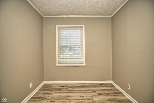 spare room featuring ornamental molding, wood finished floors, baseboards, and a textured ceiling